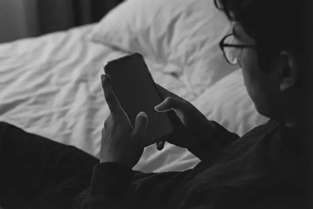 Man in bed looking at a blank phone screen